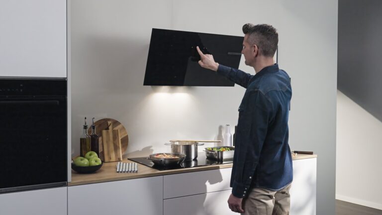 Hotte murale inclinée Bosch en verre noir allumée au-dessus d’une plaque induction, commande tactile